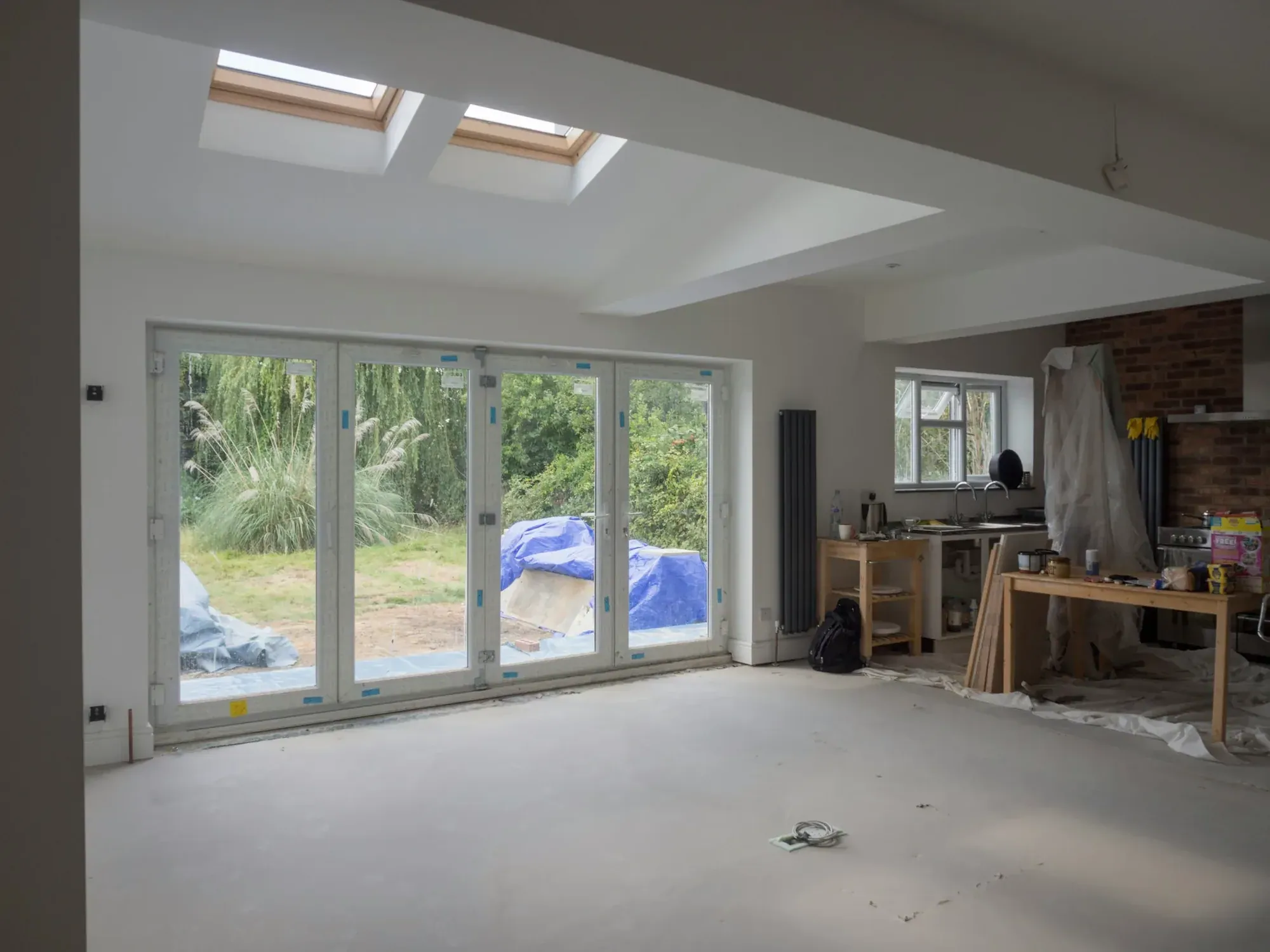 Finished extension plastered and painted white, two rooflights, bifold doors to the garden, kitchen units under protection sheets