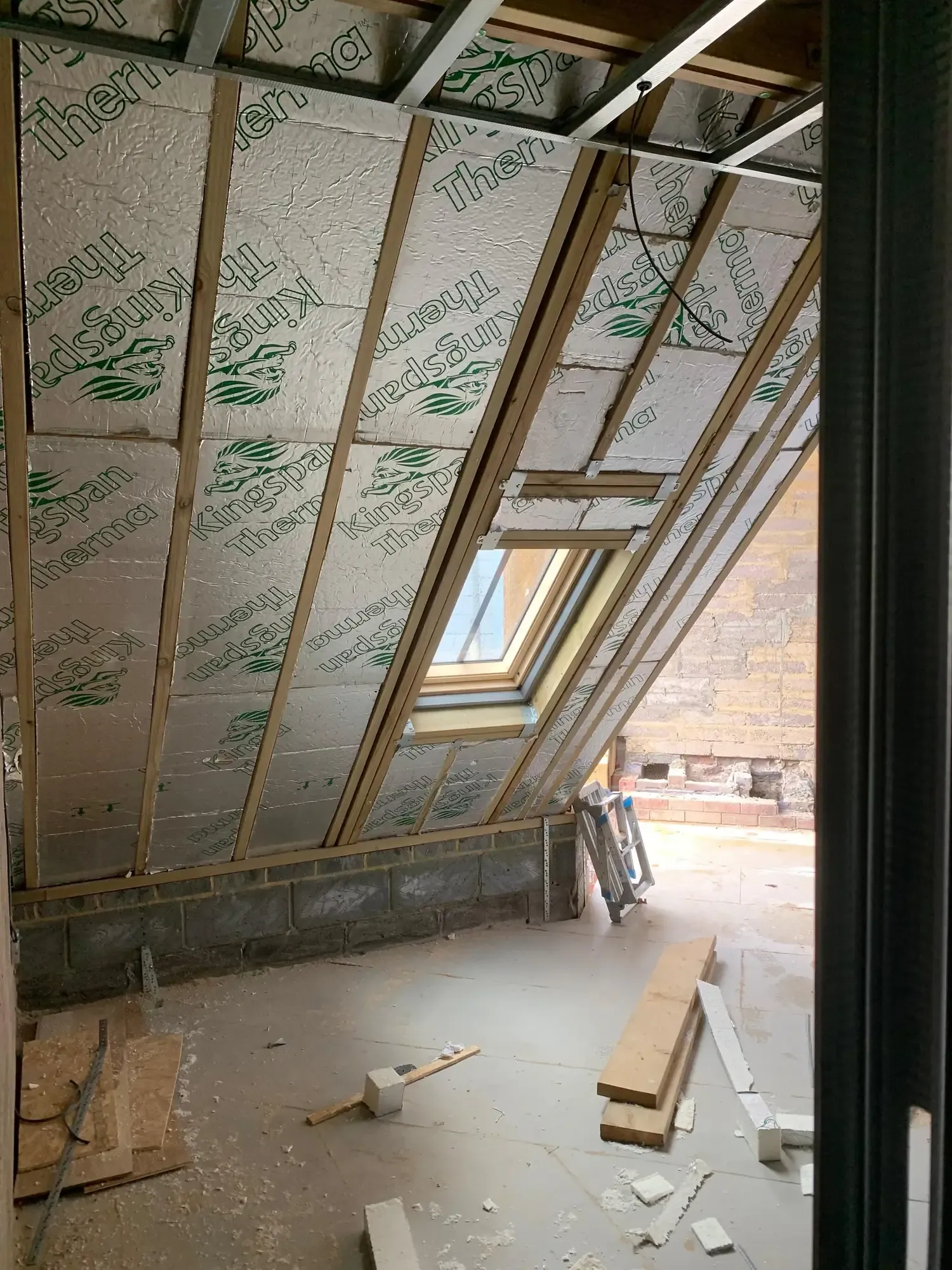Insulated roof slope with a rooflight, timber studs and boards on the floor