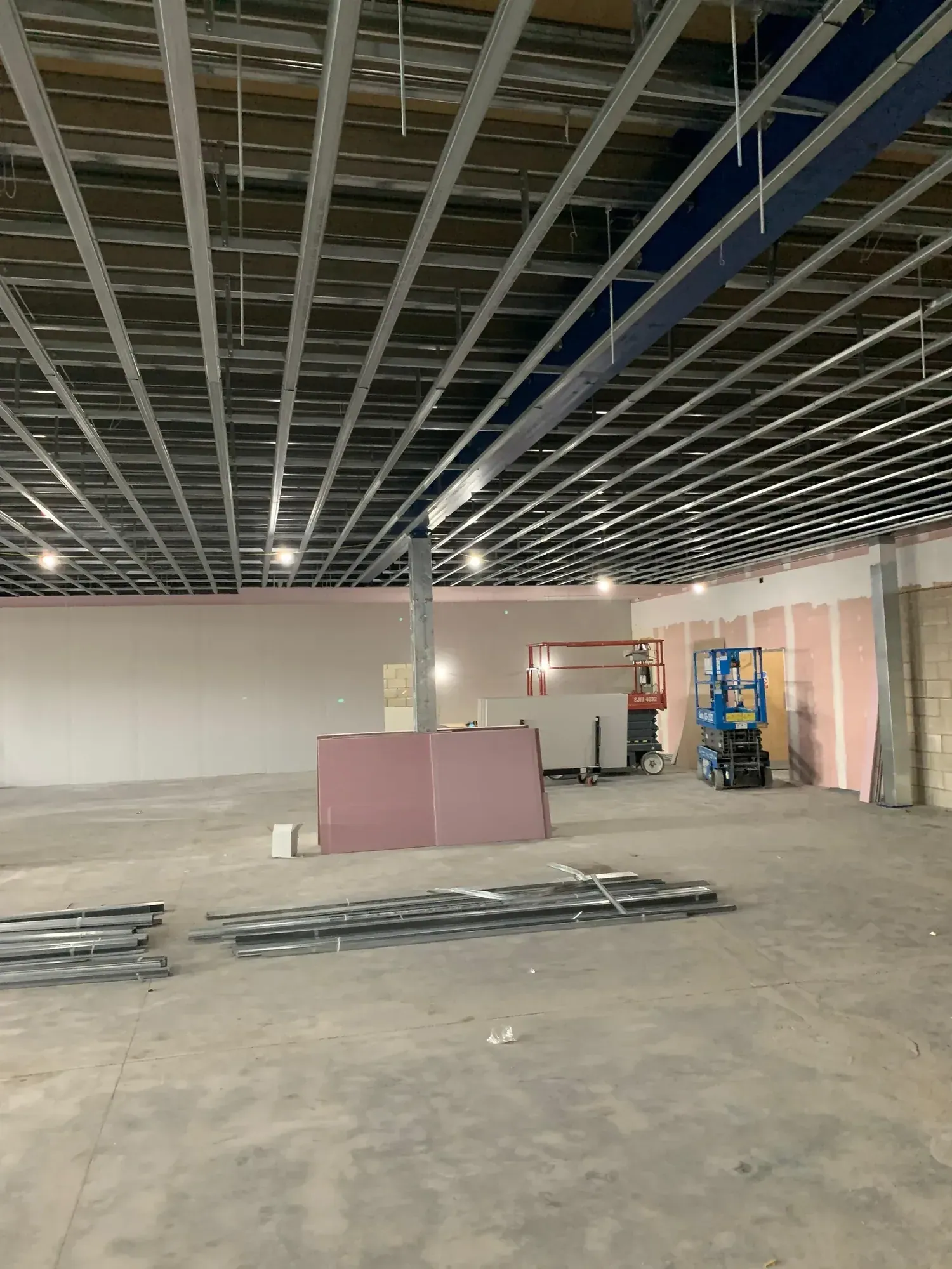 MF ceiling grid across a large open commercial floor, boards stacked below