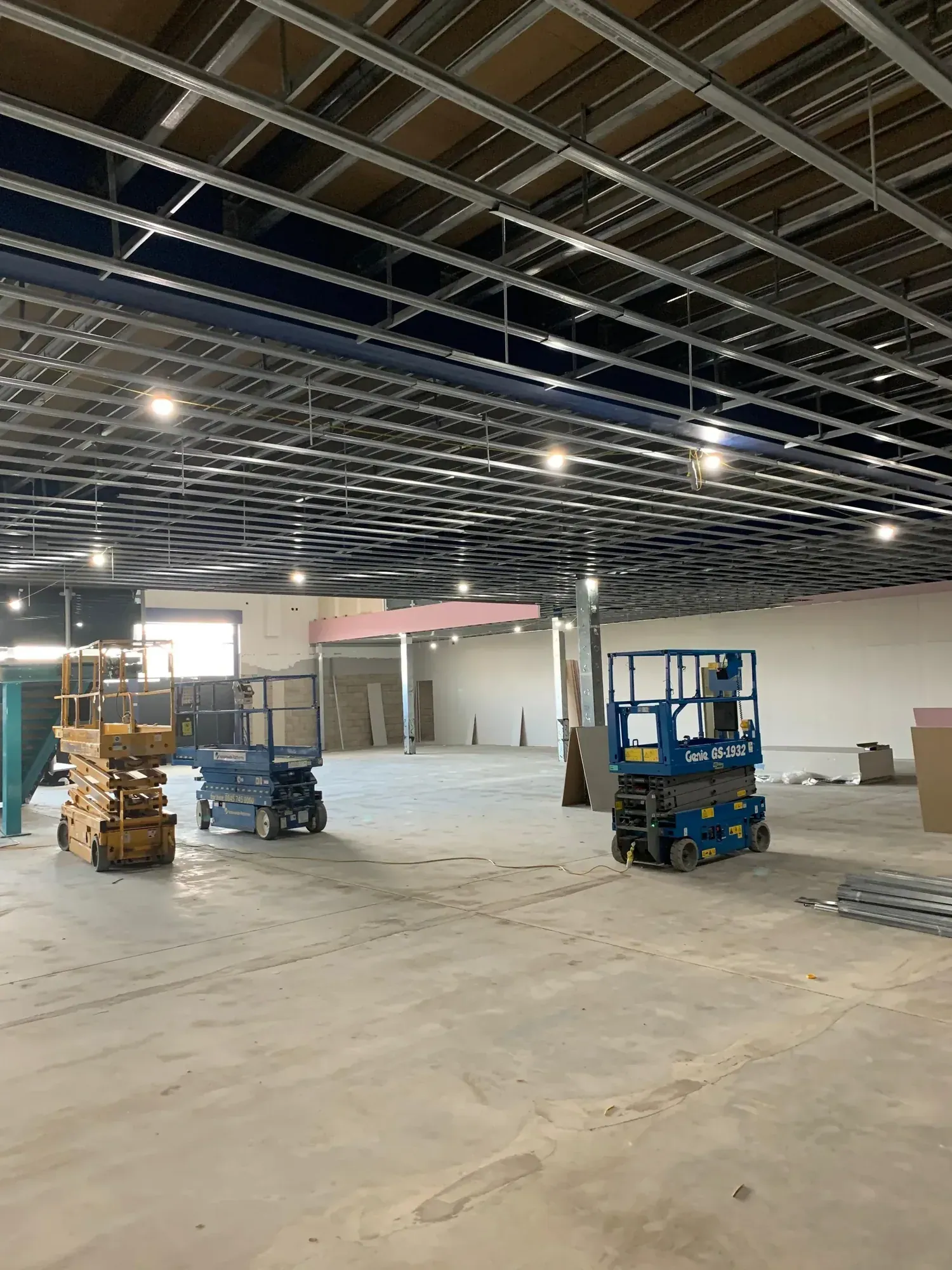 MF ceiling grid across a large open commercial floor, scissor lift beneath the grid